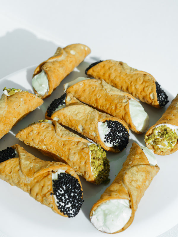 Cannoli filled with cream, finished with pistachio and chocolate pearls