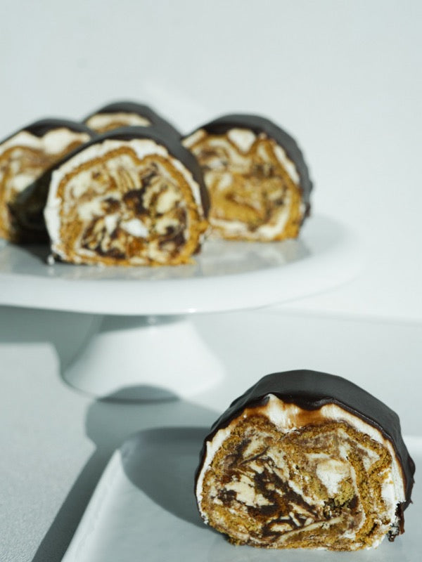 Chocolate-glazed marbled roll slices on a cake stand