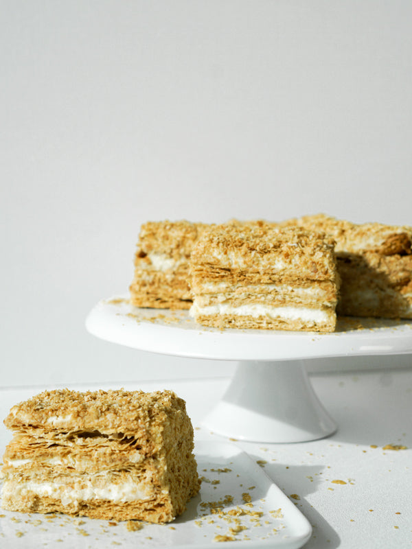 Slices of layered puff pastry and cream on a white cake stand