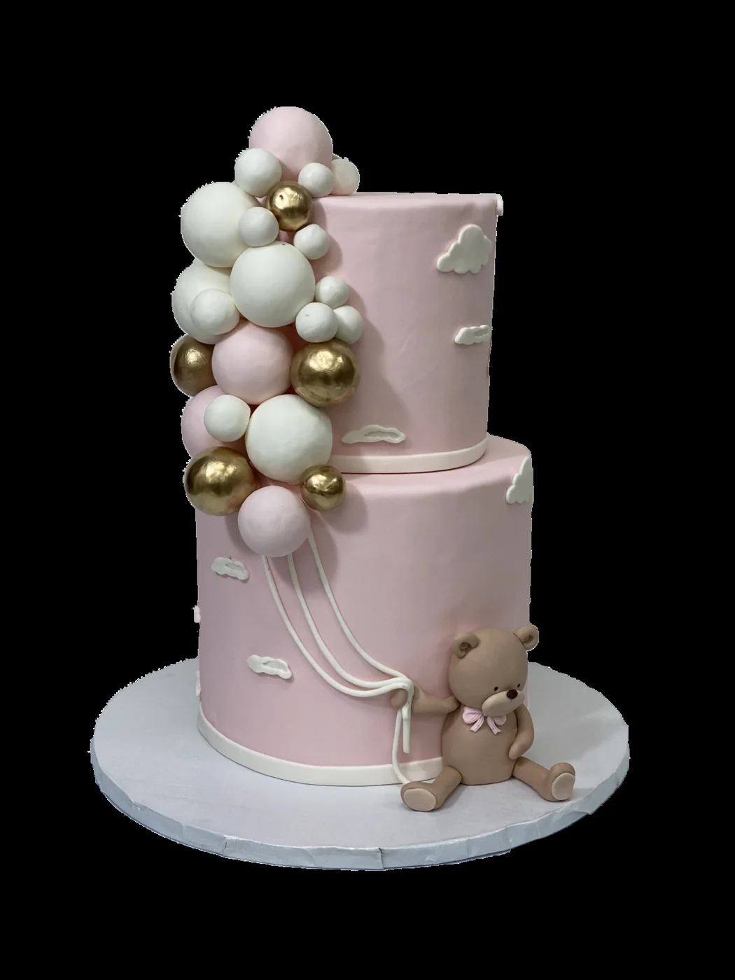 Pink celebration cake with a teddy bear and balloon decorations